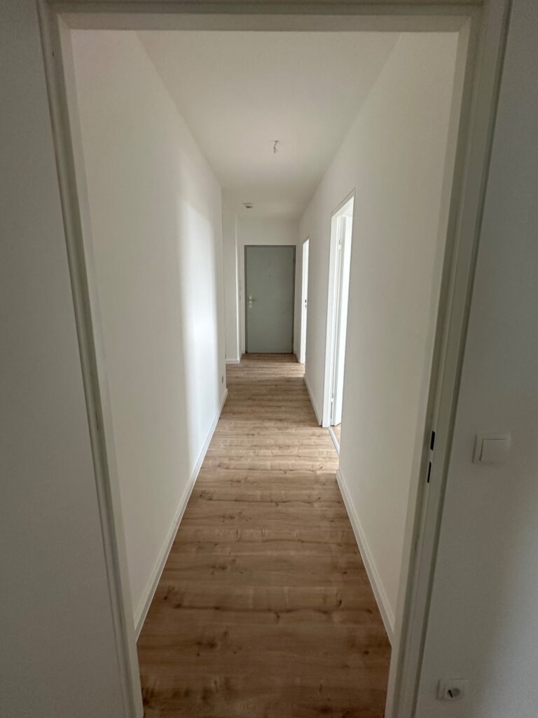 Renovierter Flur mit hellem Boden und weißen Wänden